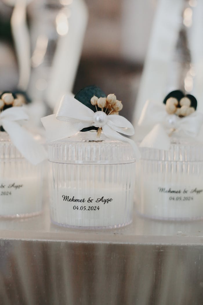 Delicate white candles in glass jars with personalized wedding labels and ribbons.