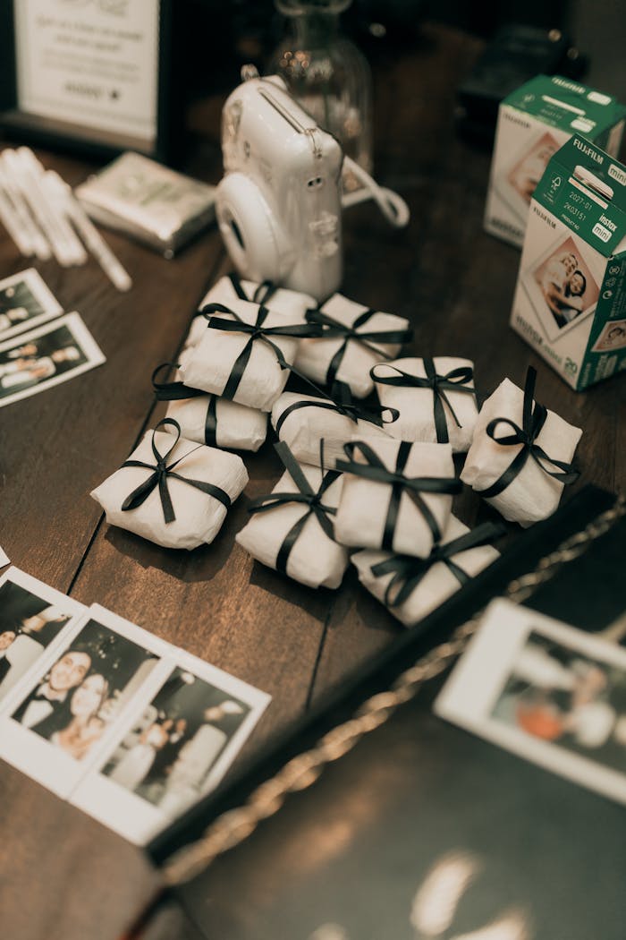 gallery-6 Stylish table setting with Polaroid camera, wrapped gifts, and instant photos creating a chic atmosphere.