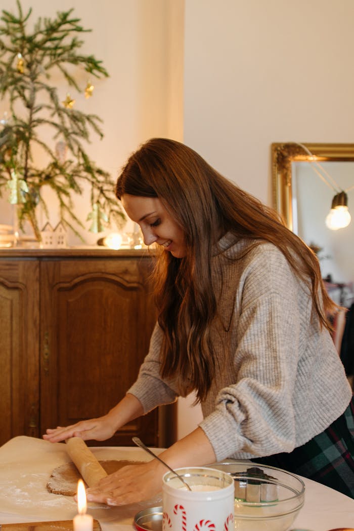 our-services-2 Caucasian woman rolling dough in a festive kitchen setting with Christmas decorations.