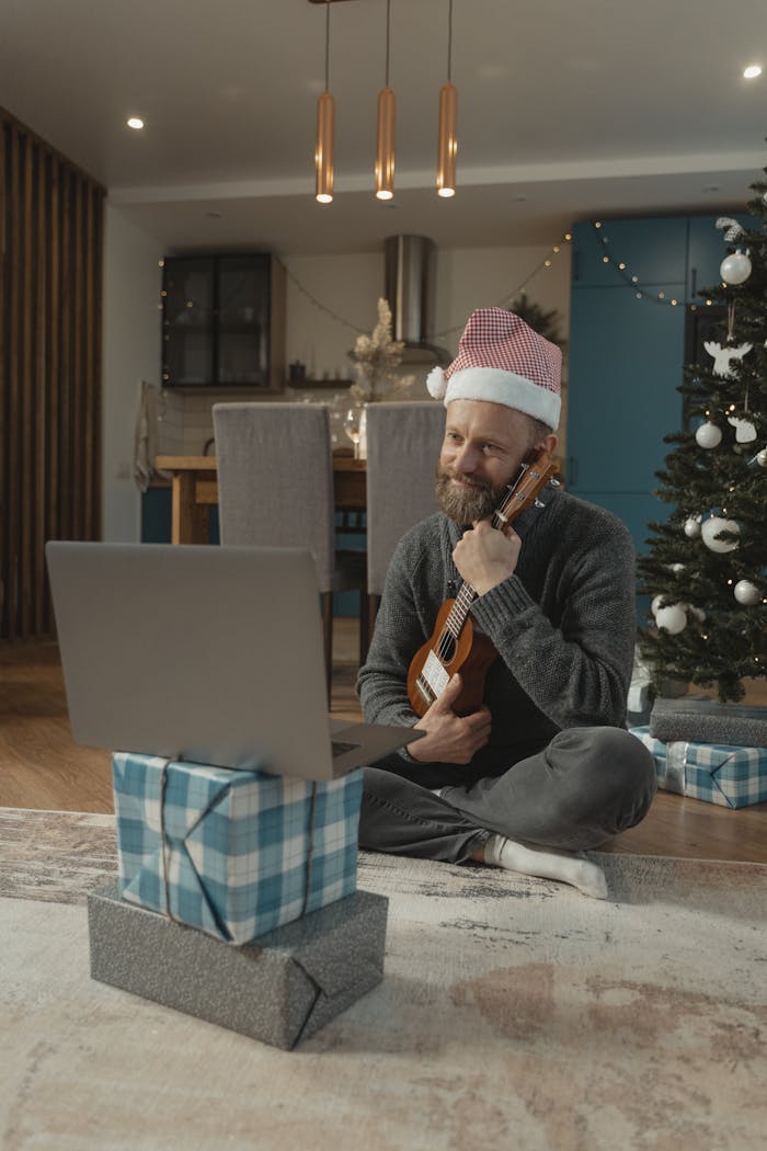 gallery-4 A man in a Santa hat plays the ukulele during a Christmas video call at home.