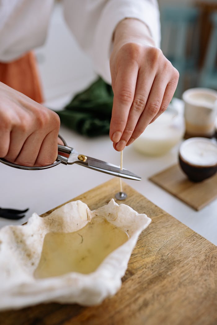 our-services-3 Close-up of a person cutting a cotton wick for a handmade candle in a shell mold. DIY creativity.