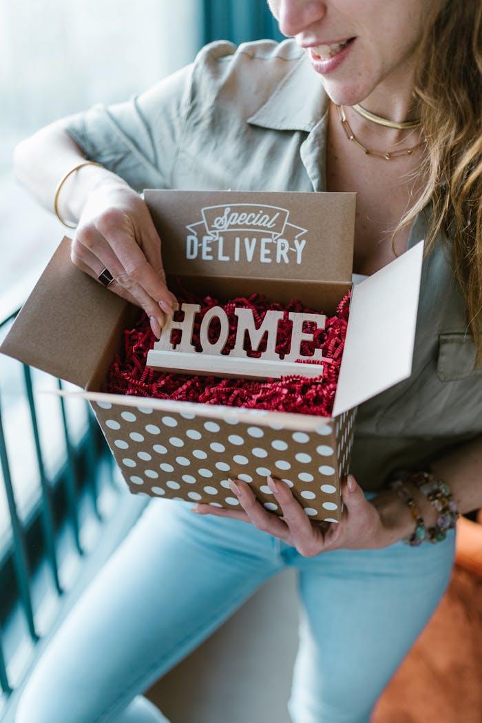 about-01 A woman opening a polka dot box labeled 'Special Delivery' with 'HOME' inside.